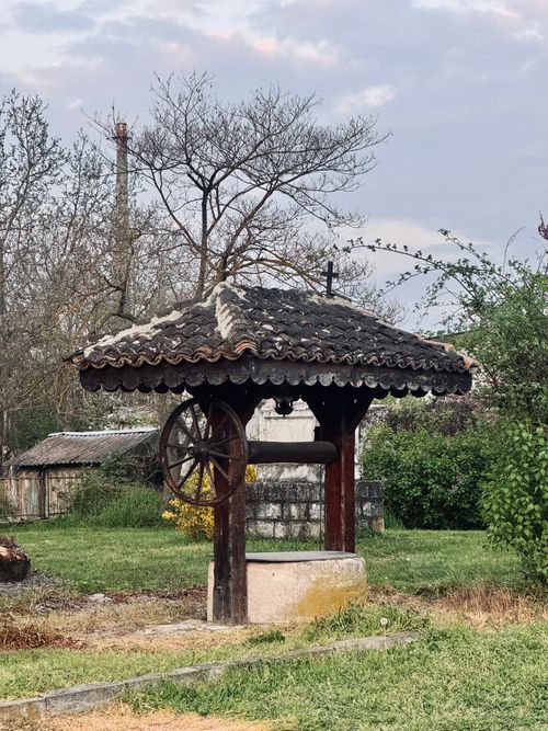 Free Vintage stone well with wooden roof in a lush countryside environment. Stock Photo