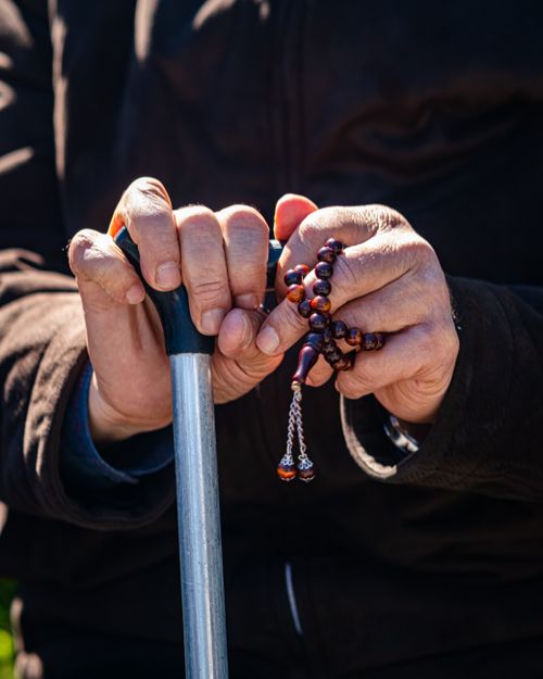 Free Close-up of senior hands on a cane, holding prayer beads, symbolizing wisdom and faith. Stock Photo