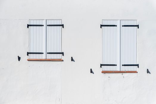 A white wall with closed shutters, showcasing a minimalist style and symmetry.