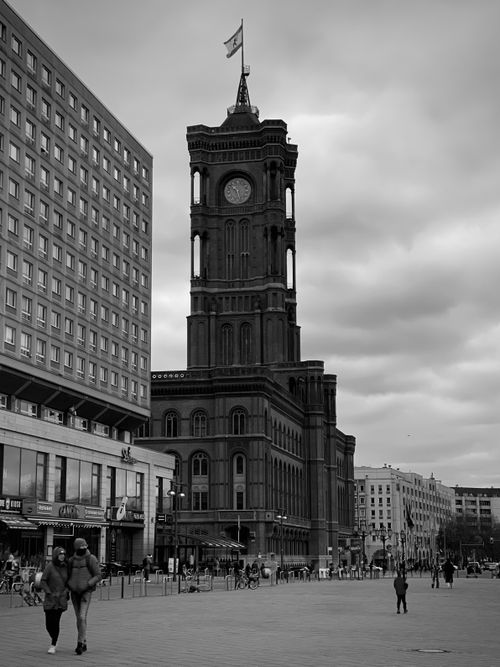 Free Black and white photo of Rotes Rathaus tower in Berlin with surrounding buildings and pedestrians. Stock Photo