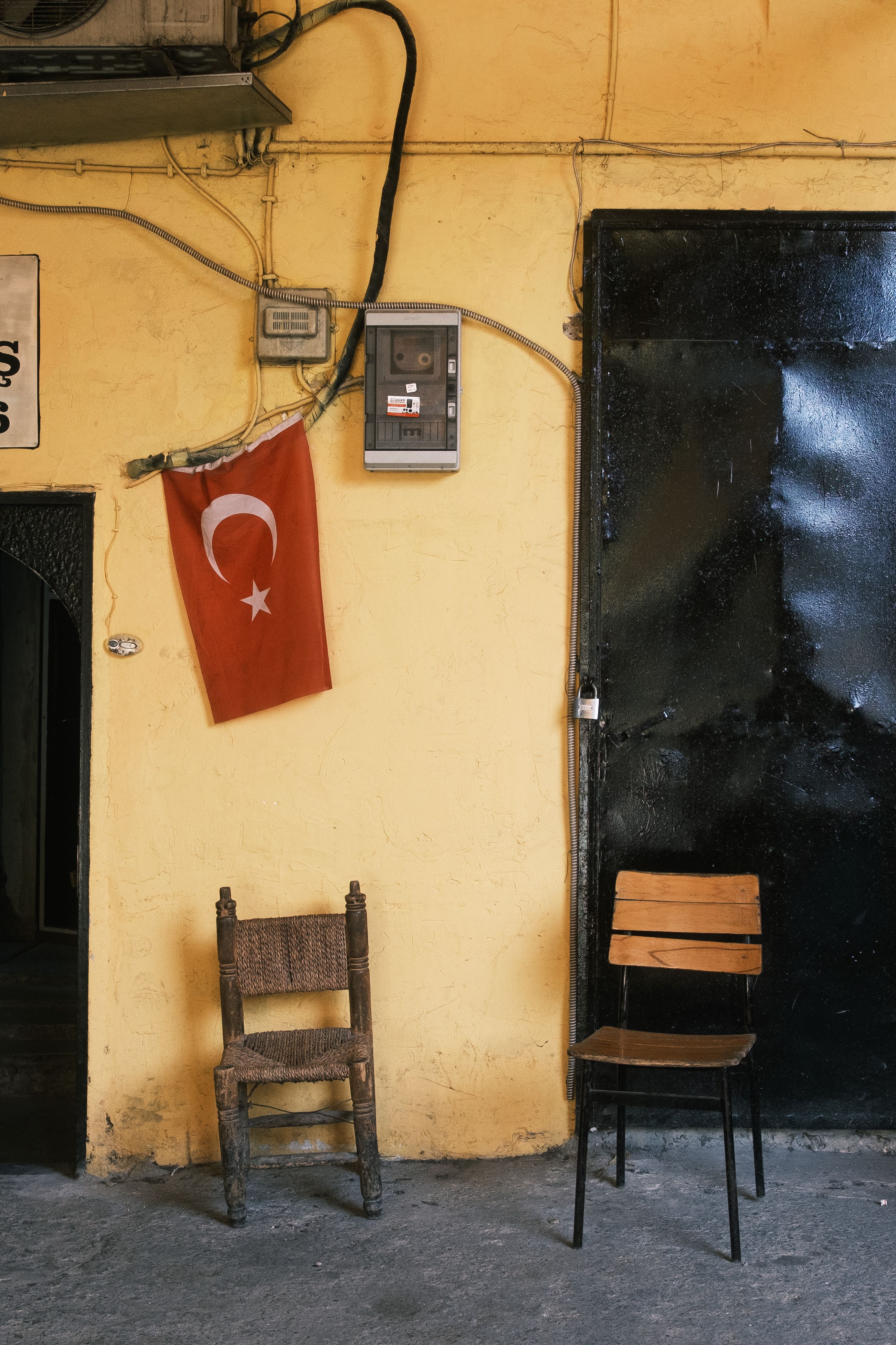 A rustic corner in İstanbul featuring a Turkish flag and vintage chairs against a vibrant wall.