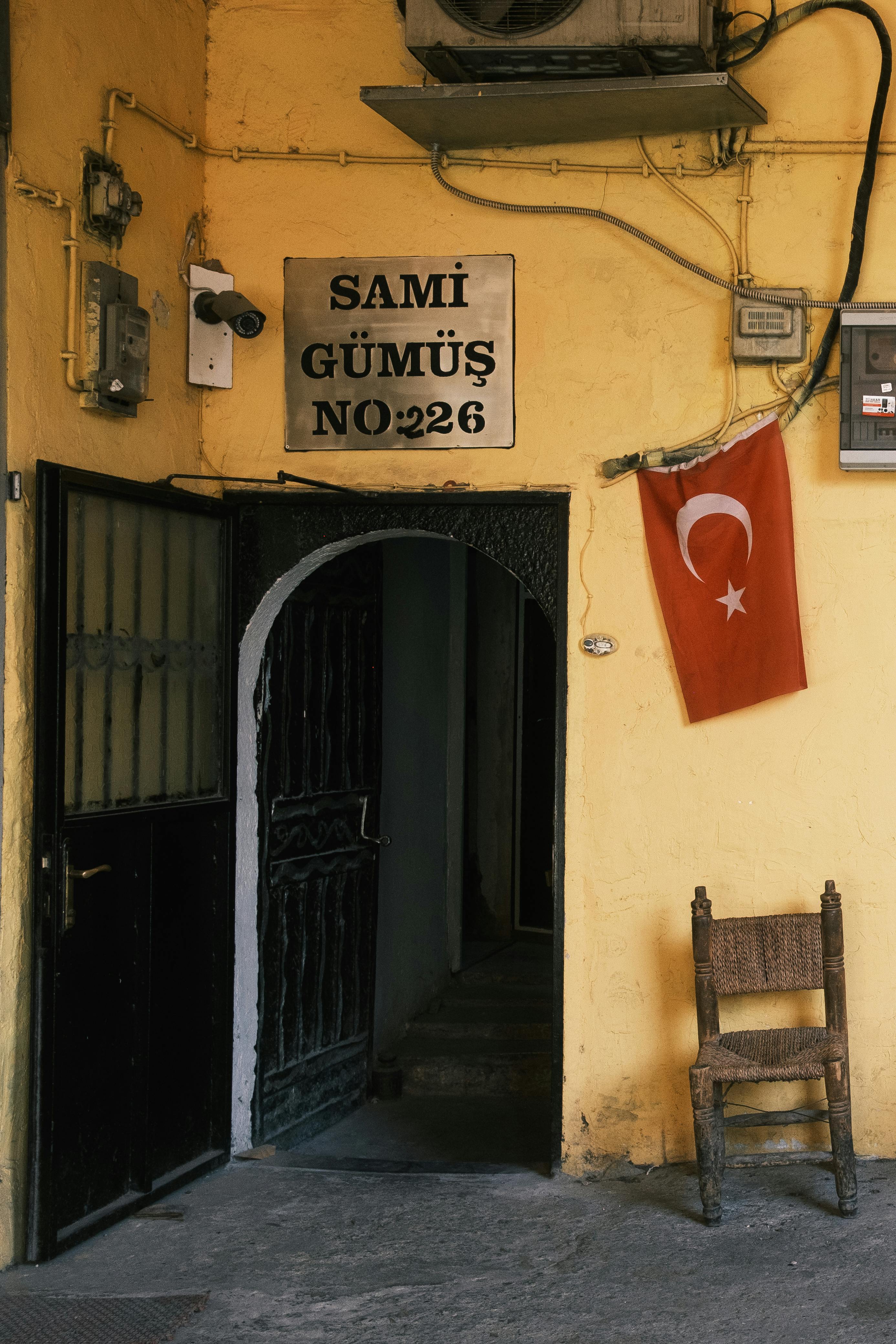 A rustic doorway in Turkey with a chair and Turkish flag, offering cultural charm.