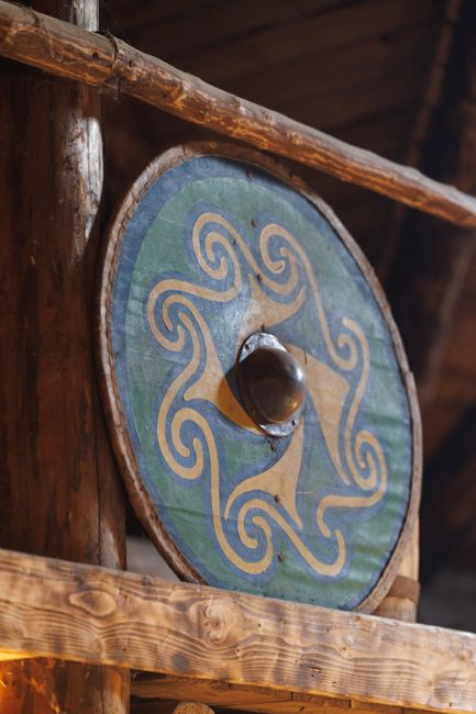 Fotomural Escudo vikingo colorido con patrón celta exhibido en una estructura de madera.