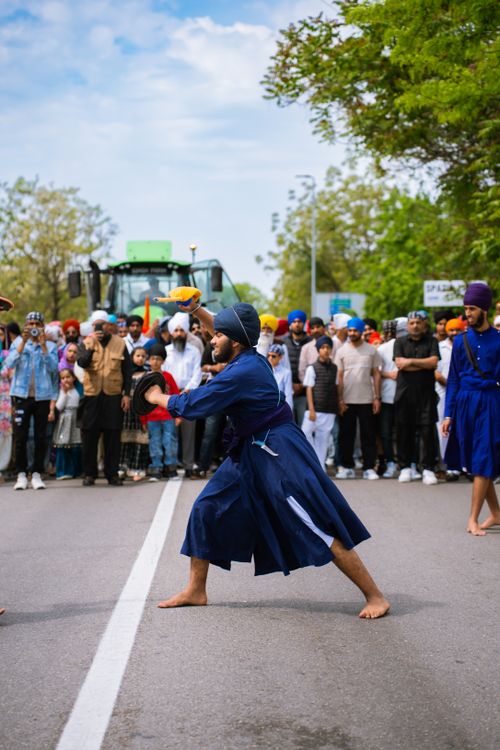 Free A group showcasing traditional martial arts in vibrant attire at a cultural festival, captivating an outdoor audience. Stock Photo