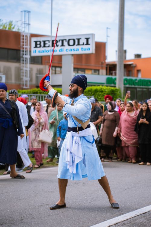 Free A Sikh man in traditional attire performs with a sword during a vibrant parade, showcasing cultural heritage. Stock Photo