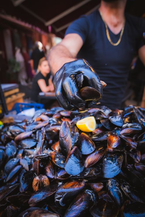 Free Fresh mussels being offered by a street vendor in İzmir, Türkiye's vibrant market atmosphere. Stock Photo