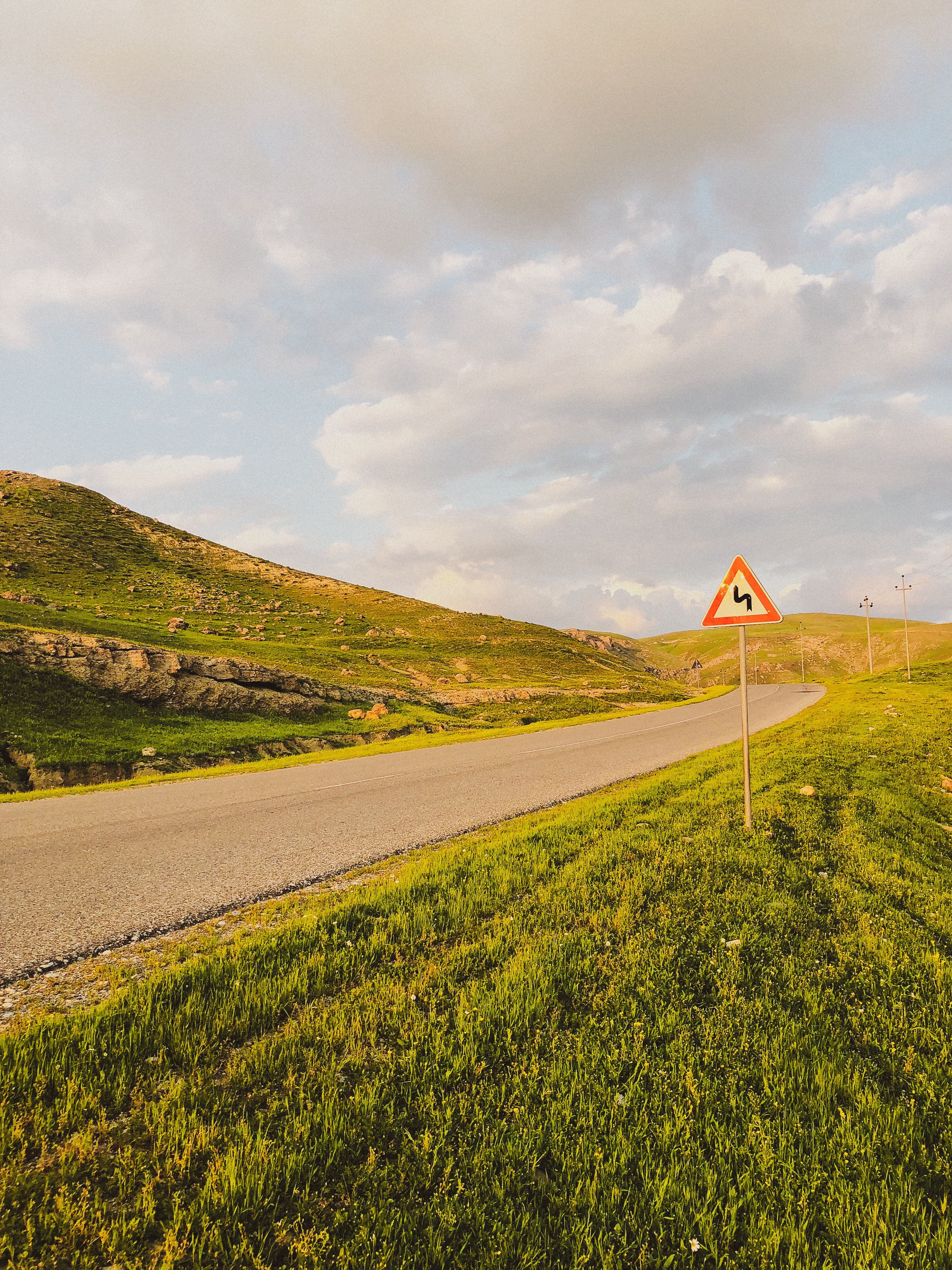 Idyllic Mountain Road with Sharp Turn Warning Sign · Free Stock Photo