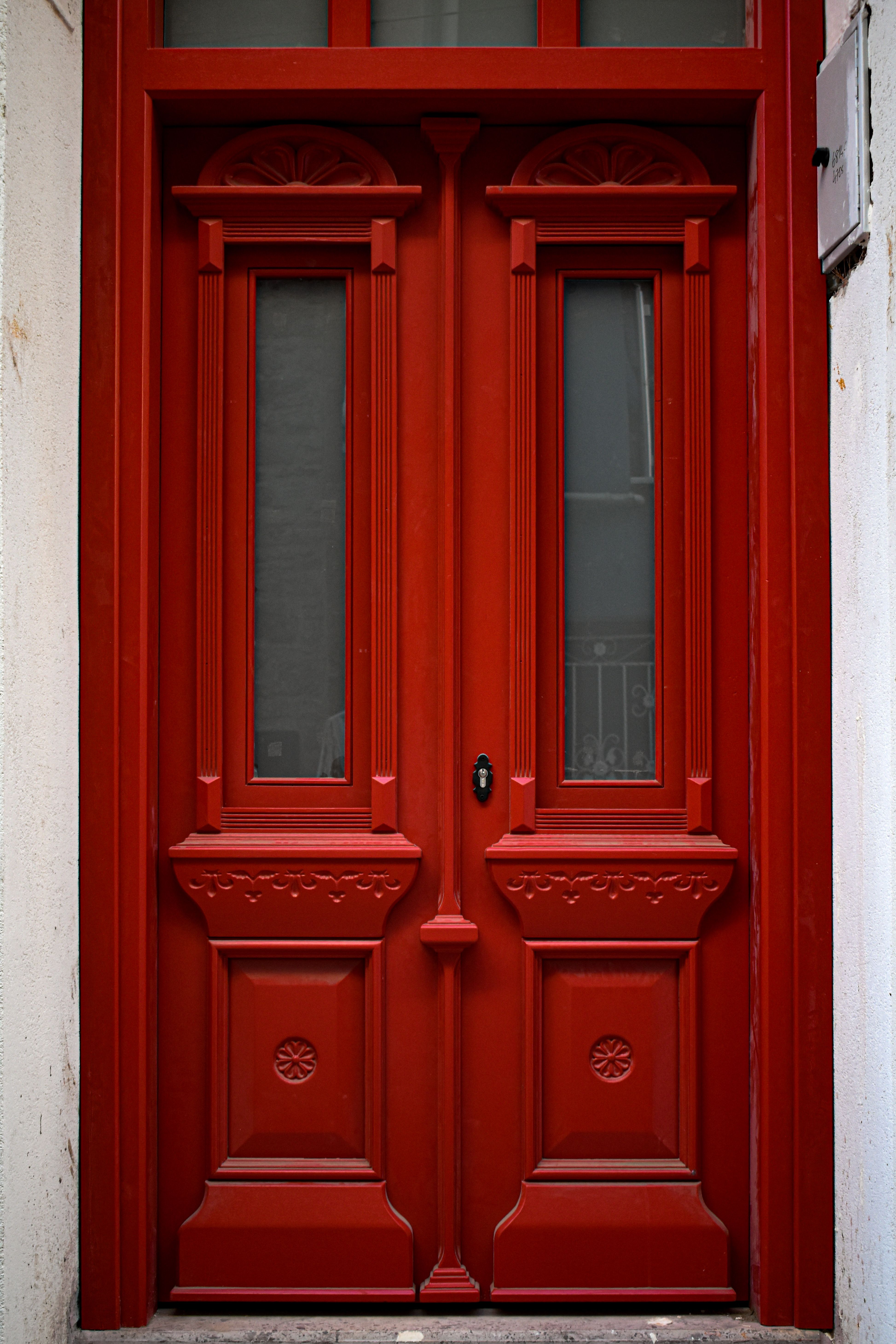 Captivating red ornate wooden door with intricate carvings in Ayvalık, Türkiye.