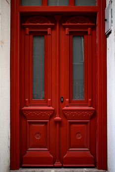 Captivating red ornate wooden door with intricate carvings in Ayvalık, Türkiye.