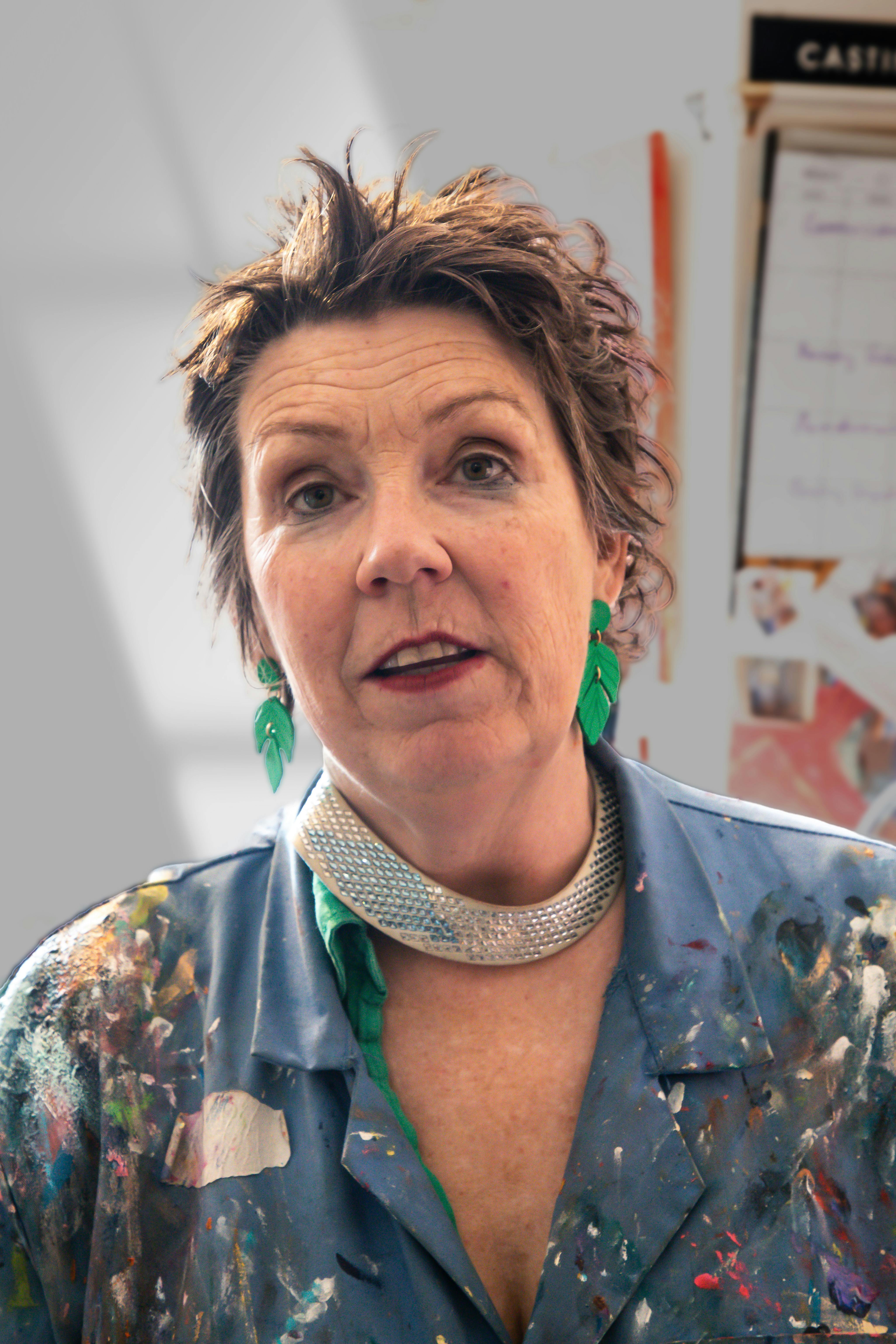 Creative portrait of a woman artist with vibrant earrings, showcasing her unique style in her studio.