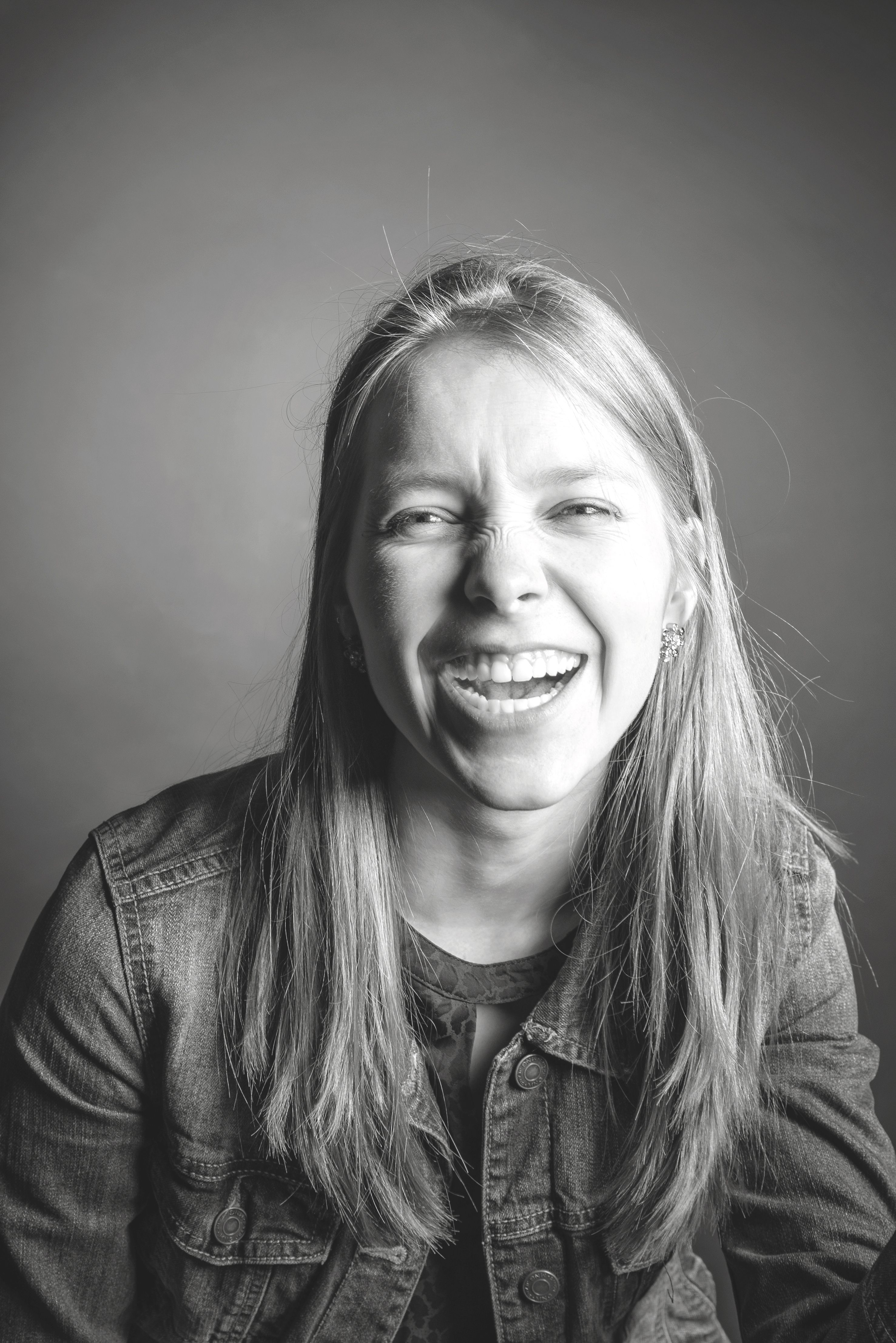 A vibrant black and white portrait capturing an adult woman laughing joyfully in a studio setting.