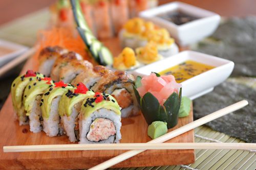 Free Close-up of a vibrant sushi platter featuring avocado rolls and chopsticks, perfect for a culinary experience. Stock Photo