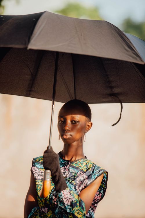Free Fashionable woman holding a black umbrella in an outdoor setting. Vibrant and stylish portrait. Stock Photo