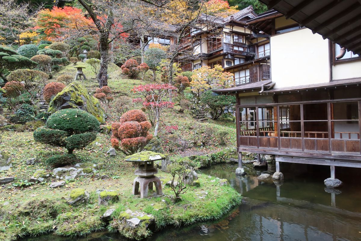 紅葉の庭園と、池に面した木造の建物（福島県会津若松市）