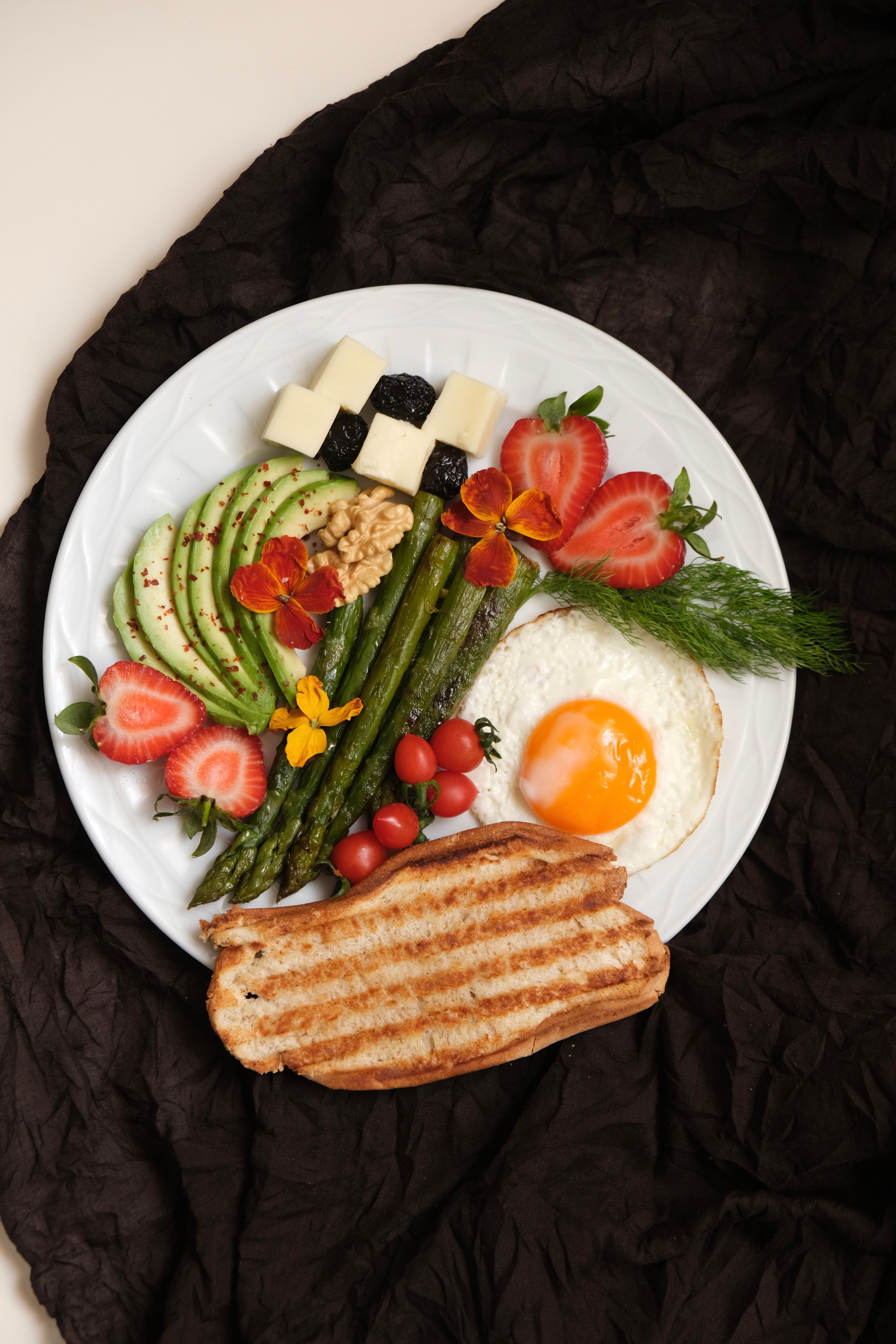 A vibrant breakfast plate featuring avocado, asparagus, eggs, and fresh fruits for a nutritious start.