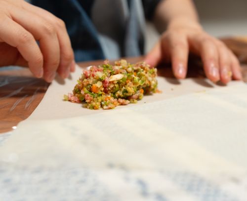 Free Hands preparing a vibrant filling for an Asian dish, showcasing culinary art in progress. Stock Photo