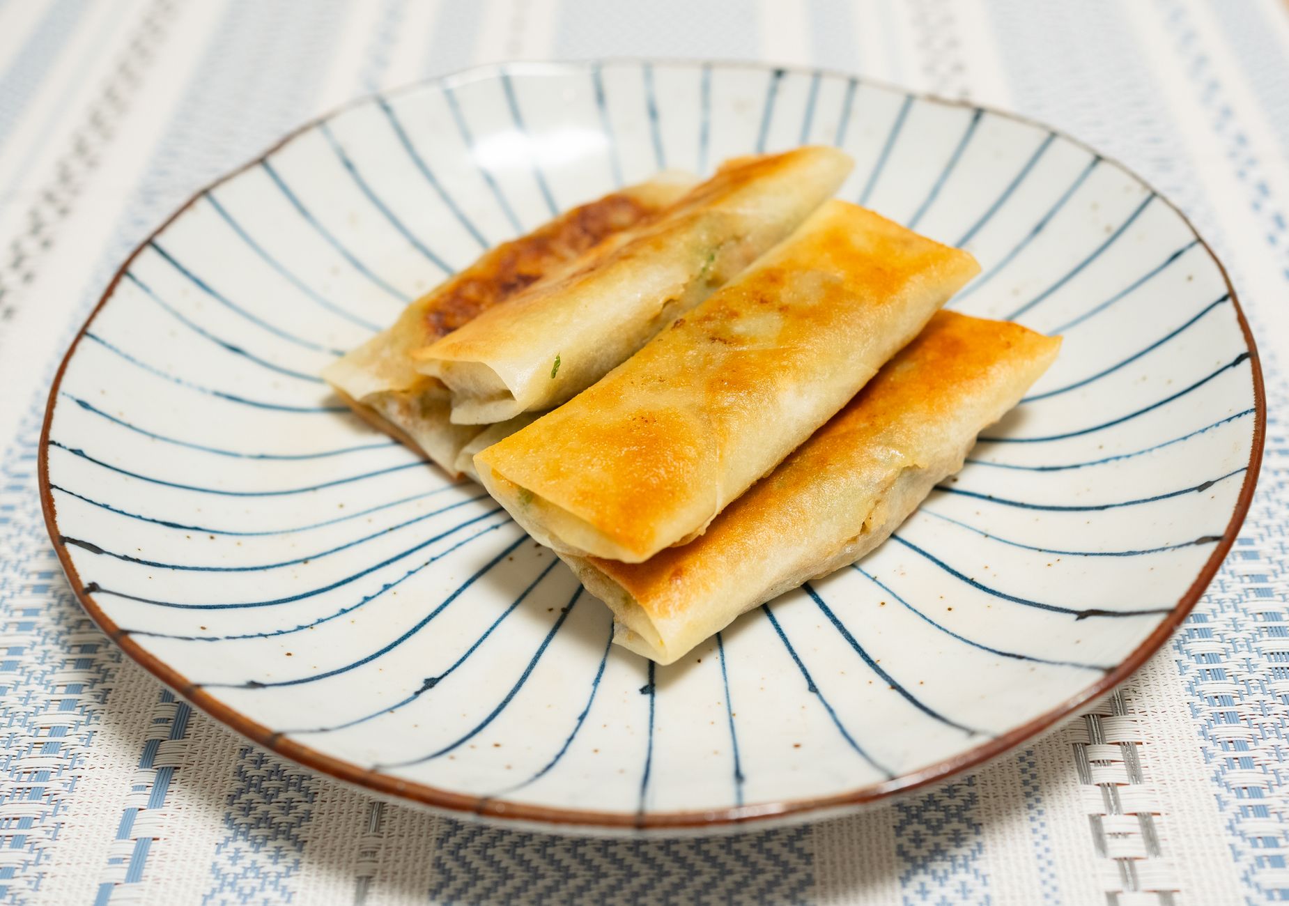 Close-up comparison of a spring roll and an egg roll side by side showing wrapper texture differences