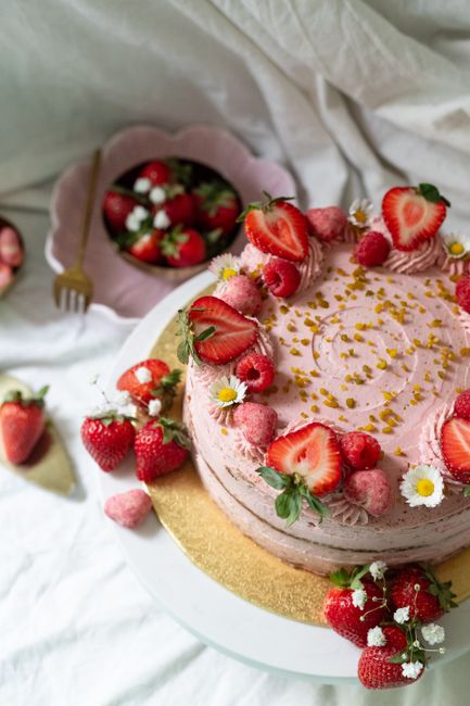 Beautiful strawberry cake topped with fresh strawberries and flowers, elegantly presented.