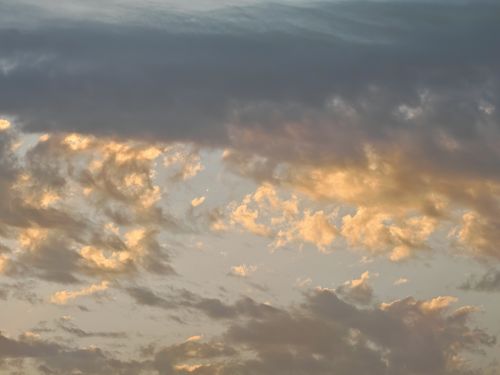 Free A mesmerizing cloudscape with golden hues at twilight, capturing nature's beauty and tranquility. Stock Photo