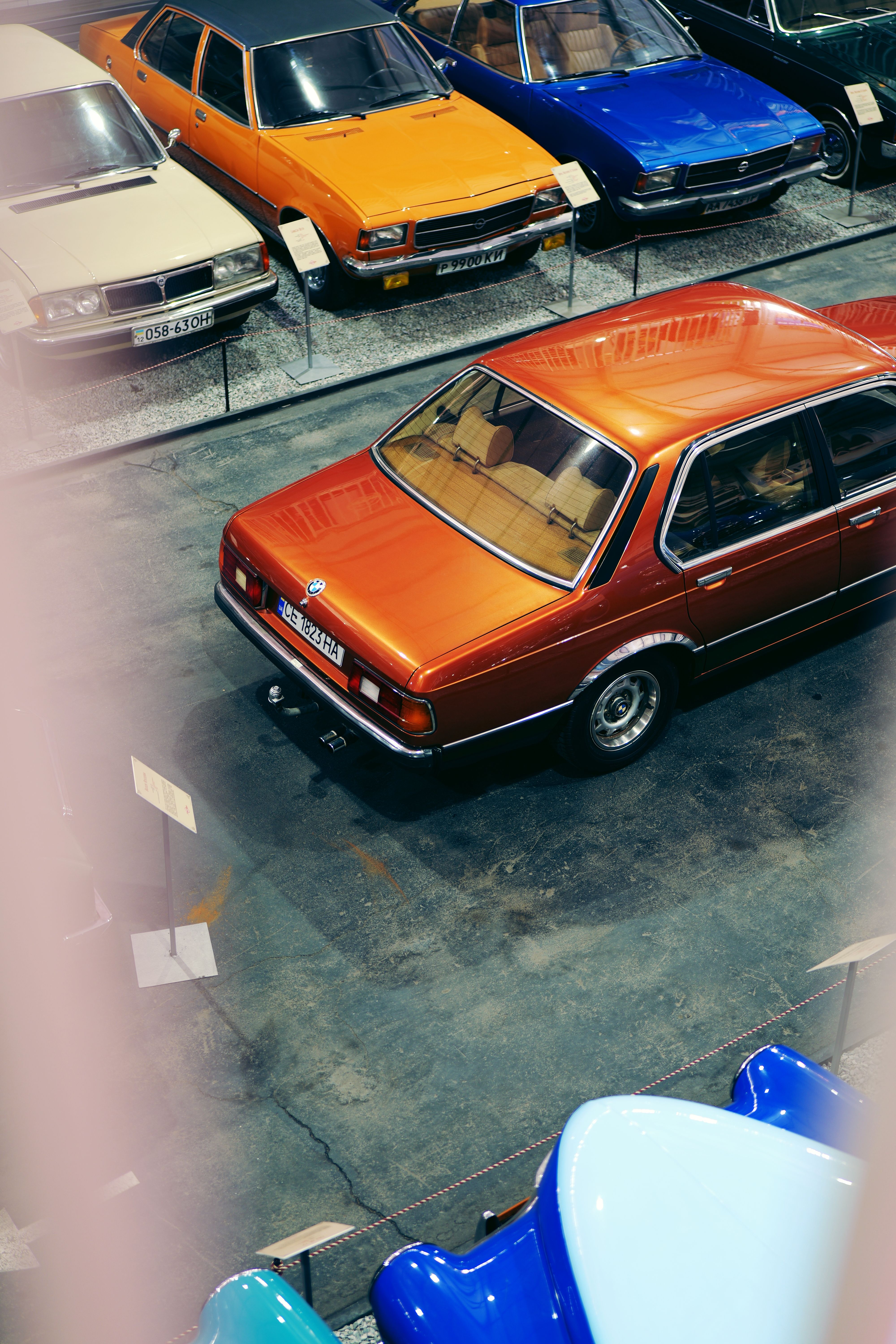 Top view of classic vintage cars in a retro-style exhibit setting, showcasing colorful designs.
