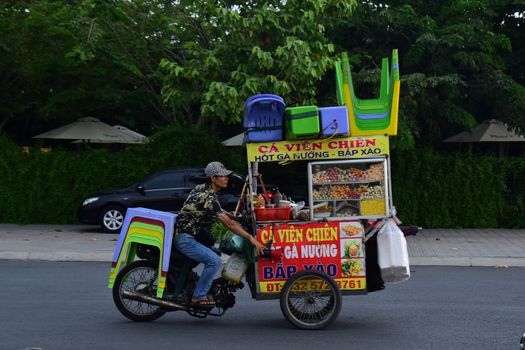 Street vendor selling Vietnamese snacks on a colorful motorbike cart outdoors.