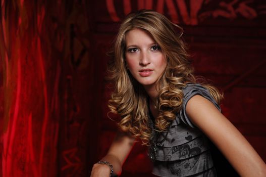 Chic portrait of a young woman with curly hair and a stylish outfit against a red artistic background.