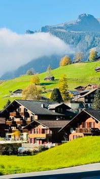 Charming alpine village in Grindelwald, Switzerland, under vibrant autumn colors and majestic mountains.
