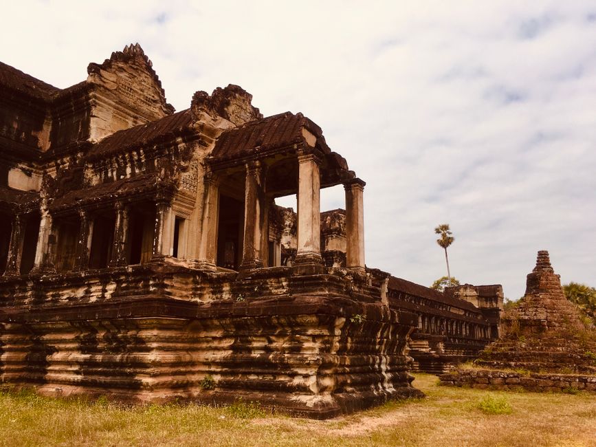 Historic Angkor Wat temple ruins with cloudy sky in Siem Reap, Cambodia, showcasing ancient architecture.