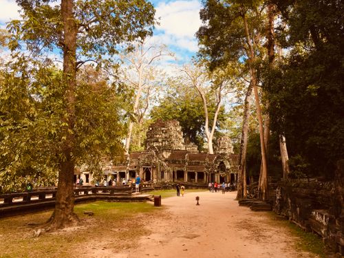 Free Majestic view of Angkor Wat temple in Siem Reap surrounded by lush trees under a bright sky. Stock Photo