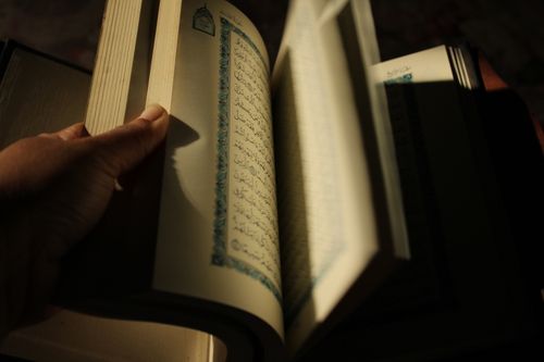 Free A hand turns the pages of an open book with script in dim light, creating a contemplative mood. Stock Photo