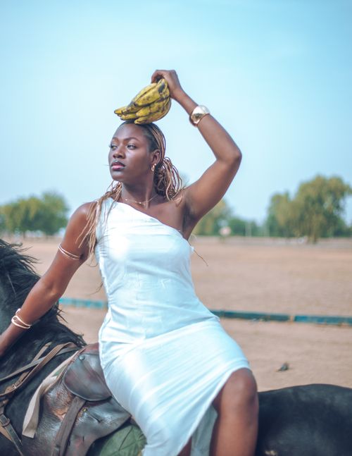 Free Artistic portrait of a woman on horseback balancing plantain, shot outdoors in Zaria, Nigeria. Stock Photo