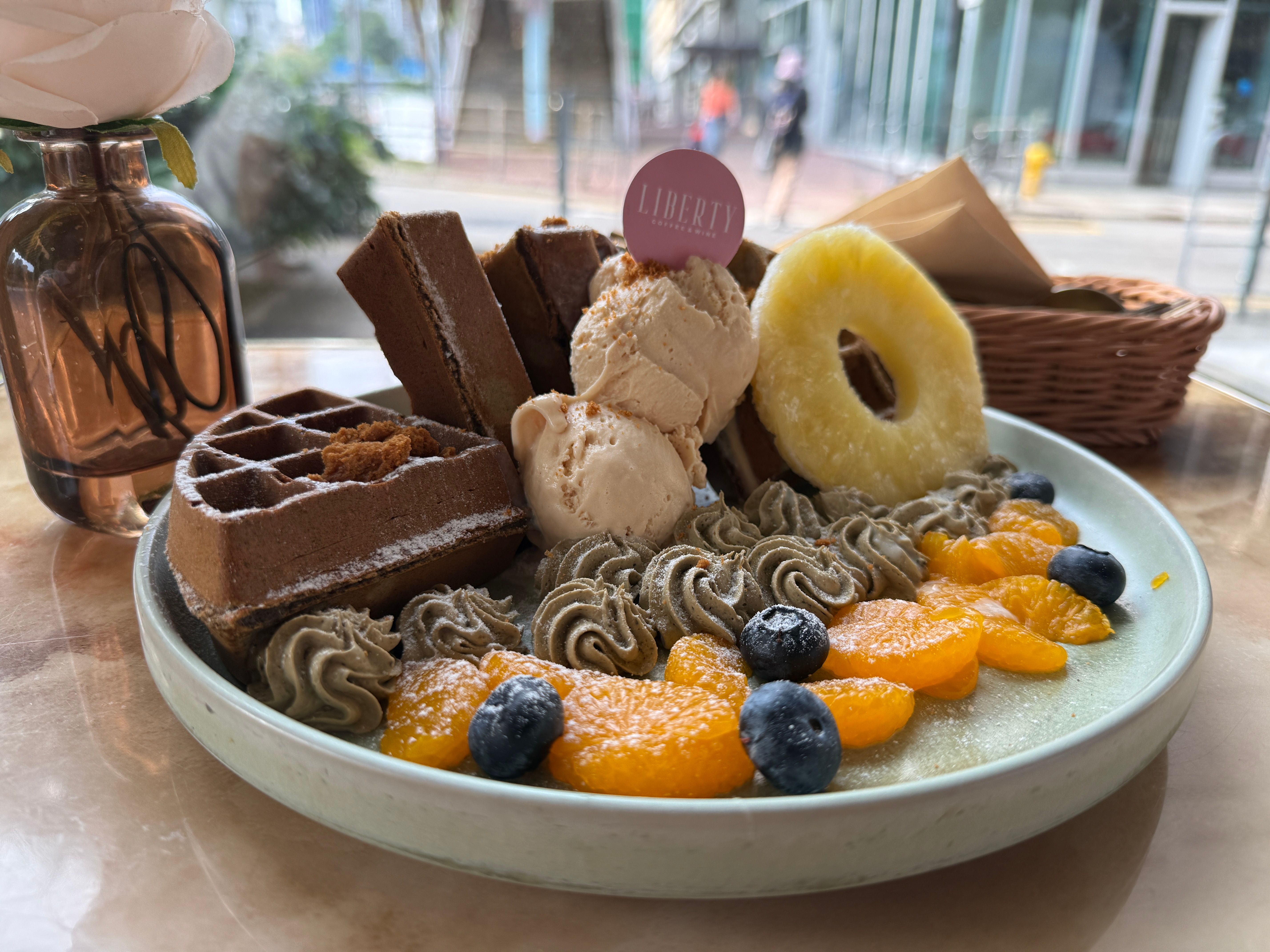 A tempting platter of waffles, ice cream, fruits, and frosting in a cafe setting.