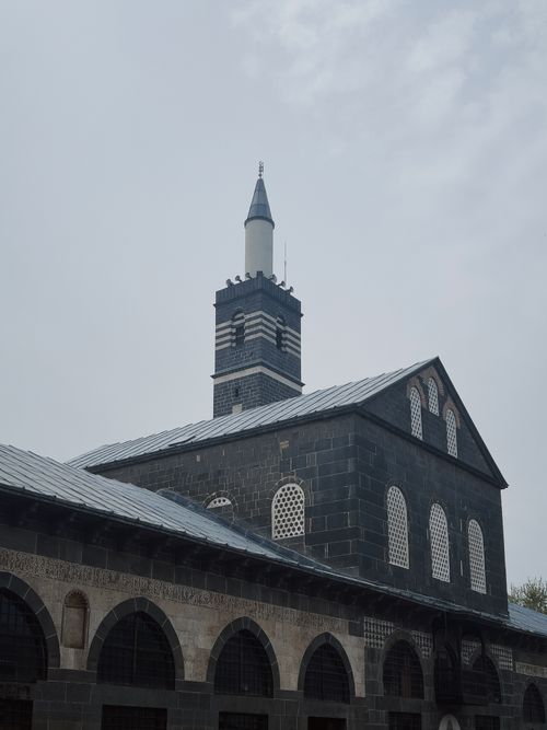 Free A historic mosque with a striking minaret set against an overcast sky, highlighting intricate architecture. Stock Photo