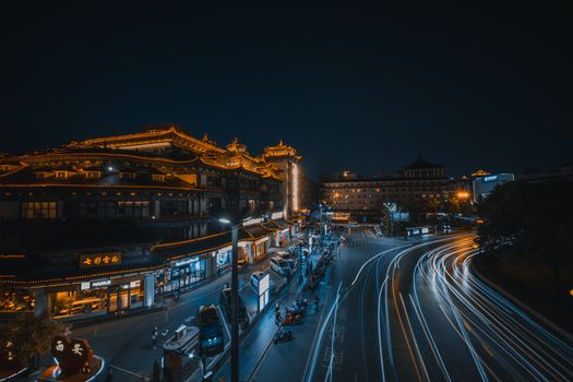 Dynamic night capture of bustling city streets and illuminated traditional architecture.