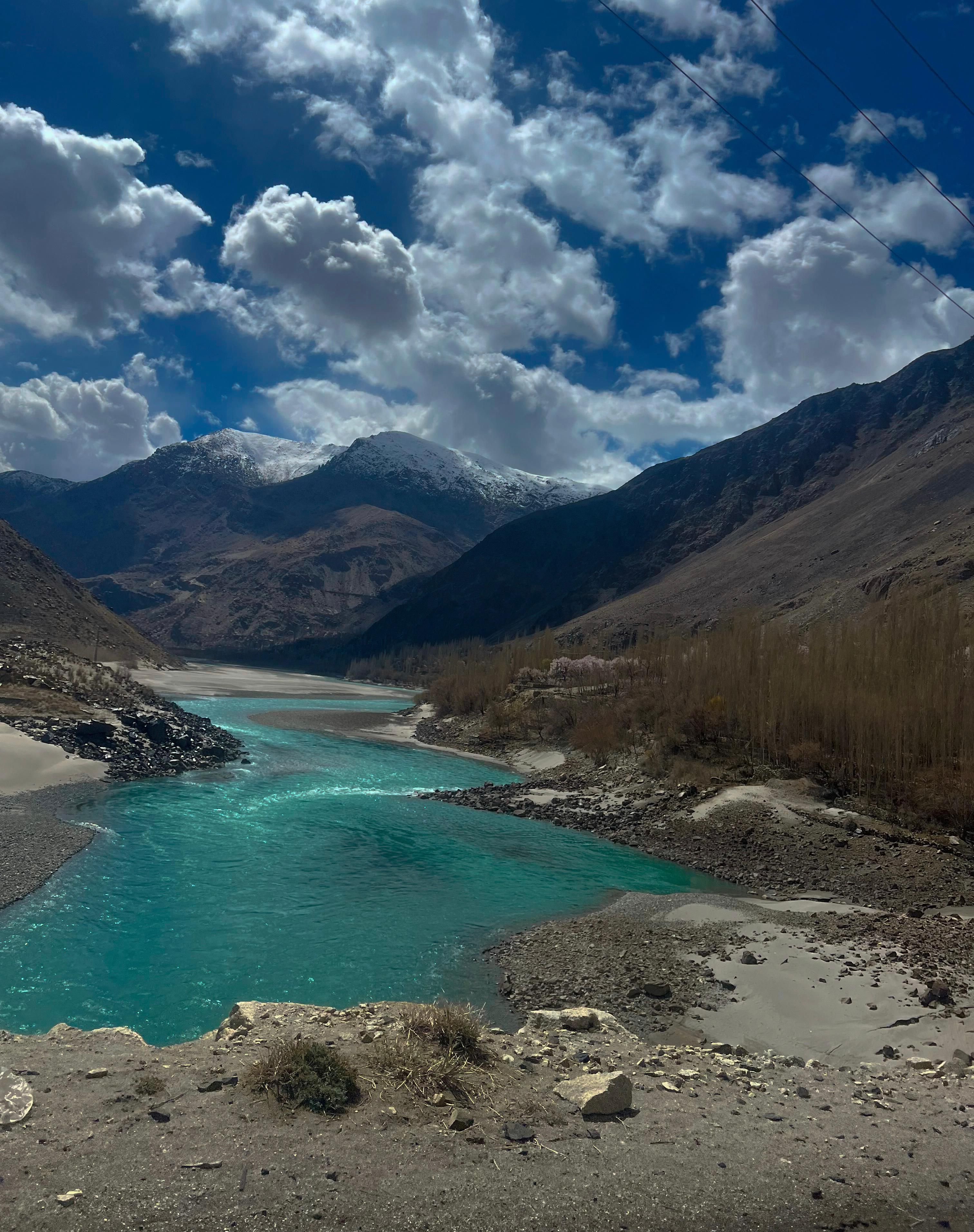 Breathtaking view of turquoise river flowing through Skardu Valley in Pakistan, framed by majestic mountains.