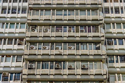 Free A detailed view of a brutalist building's symmetrical facade in New Delhi, featuring numerous air conditioning units. Stock Photo