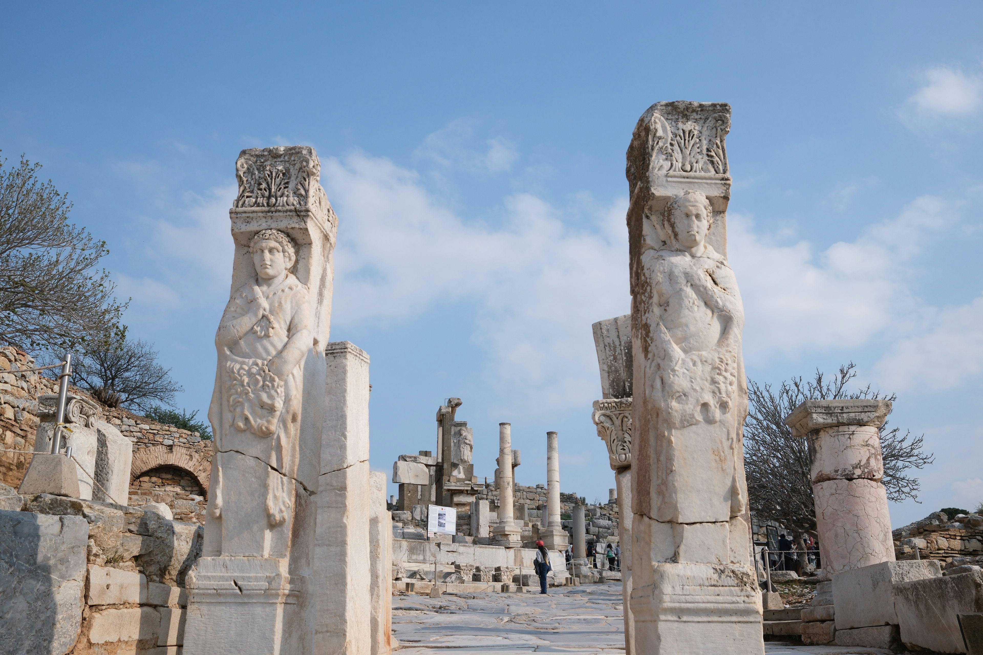 Explore the detailed ancient Roman statues and pillars in the historic ruins of Ephesus, Turkey.