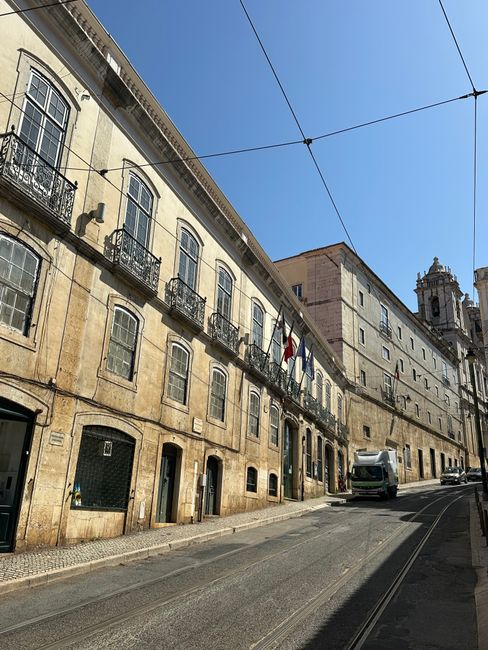 Explore a sunlit urban street in Lisbon showcasing classic architecture and vibrant city life. — Intendente, Portugal.