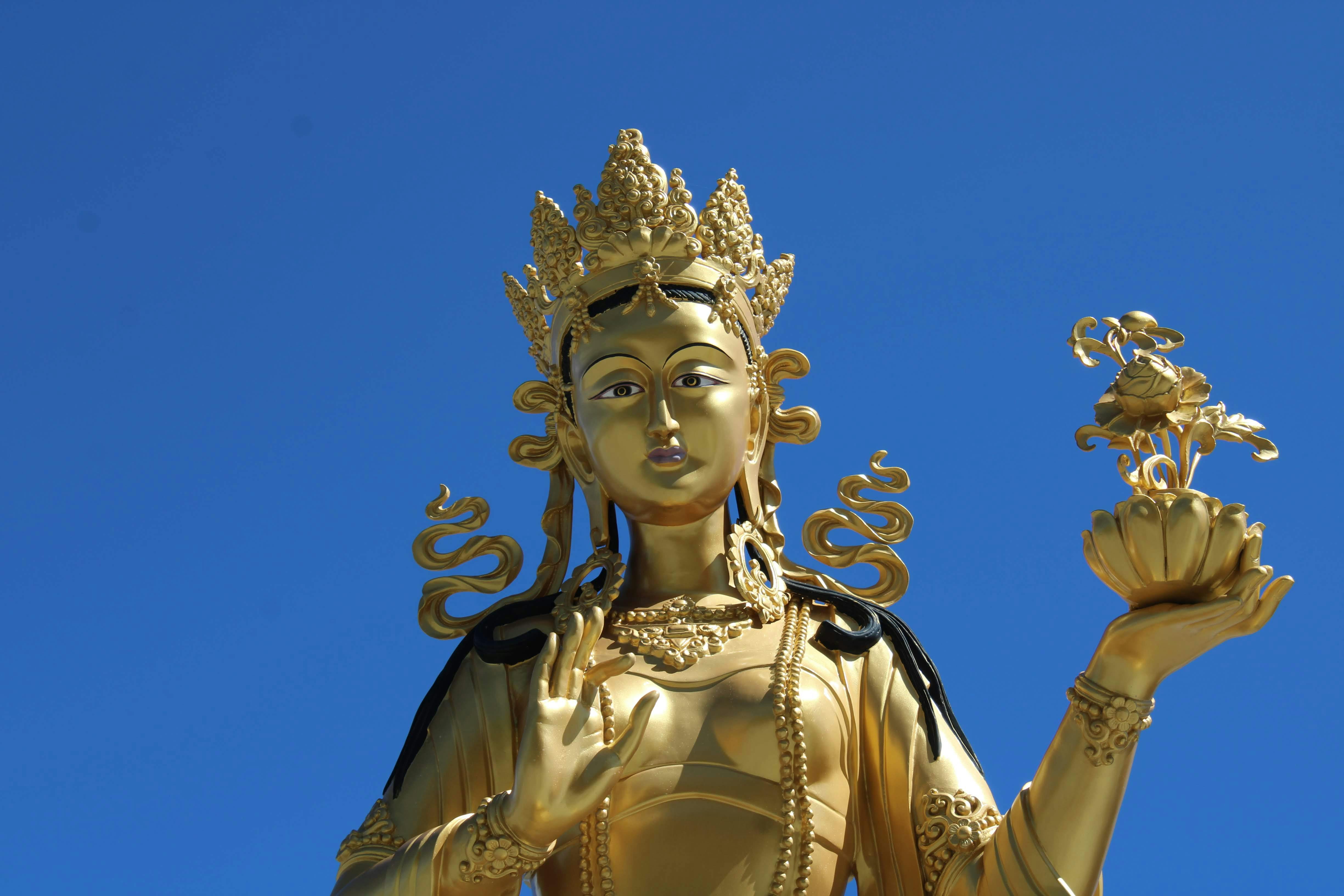 A stunning golden Buddha statue against a vivid blue sky highlighting its intricate design and spiritual presence.