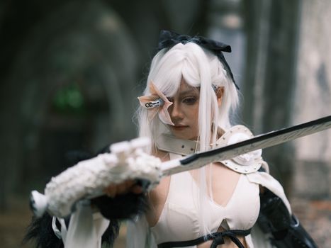 A striking portrait of a cosplayer with sword in an outdoor setting.