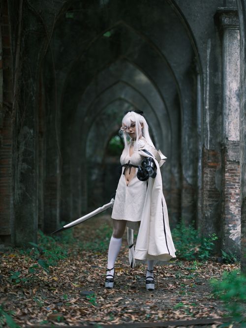 Free A cosplayer in a mysterious costume poses in a historical archway, creating a fantasy ambiance. Stock Photo