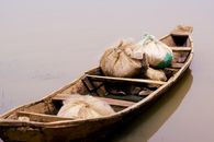 A rustic wooden boat carrying sacks floats peacefully on still waters in Minna, Nigeria.