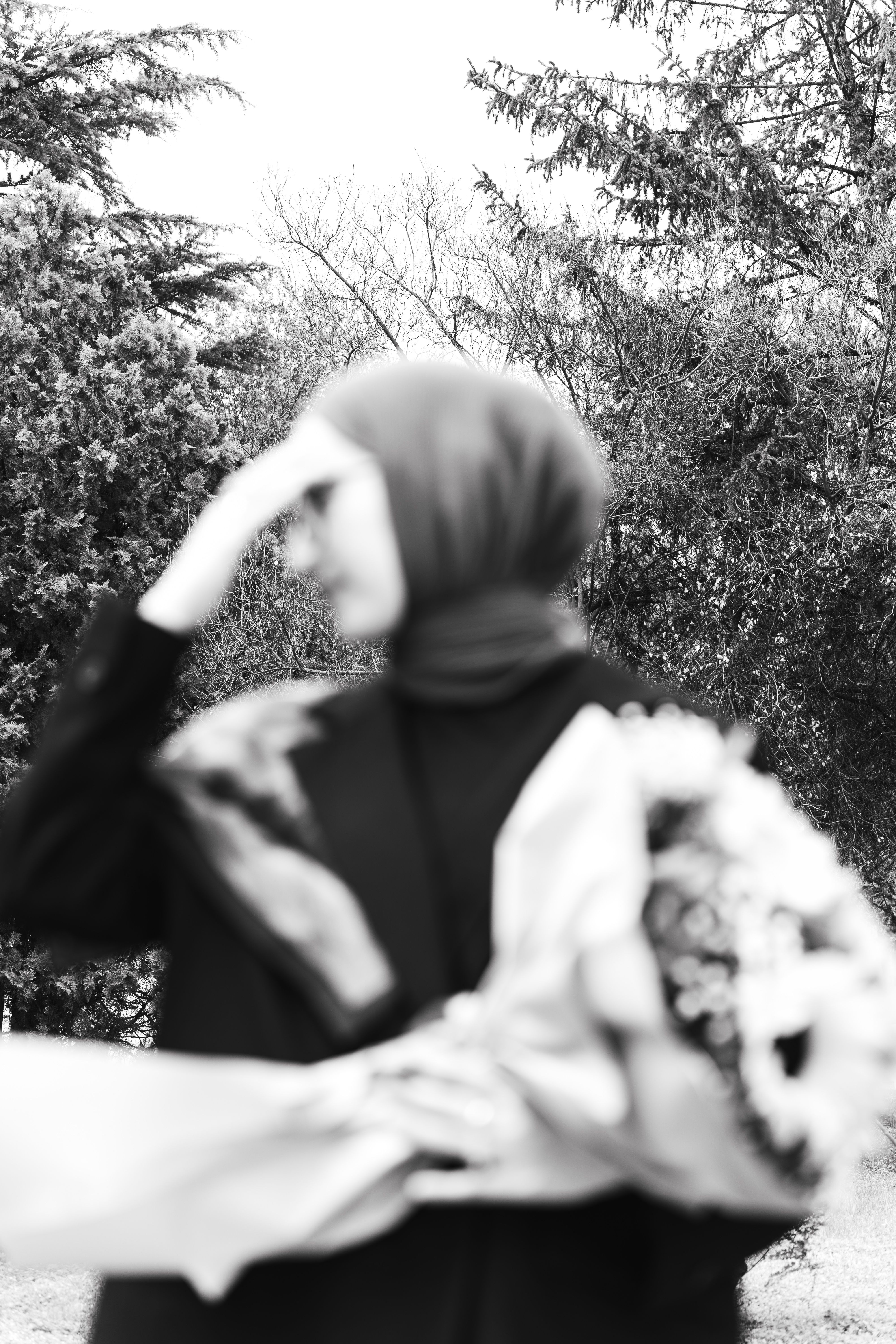 Artistic black and white photo of a blurred person holding a bouquet outdoors.
