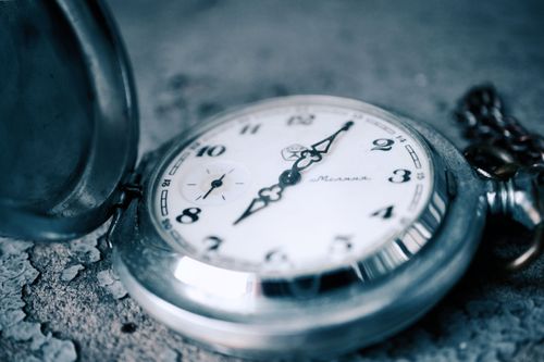 Free Close-up of a vintage pocket watch featuring intricate details and a classic design on a textured surface. Stock Photo