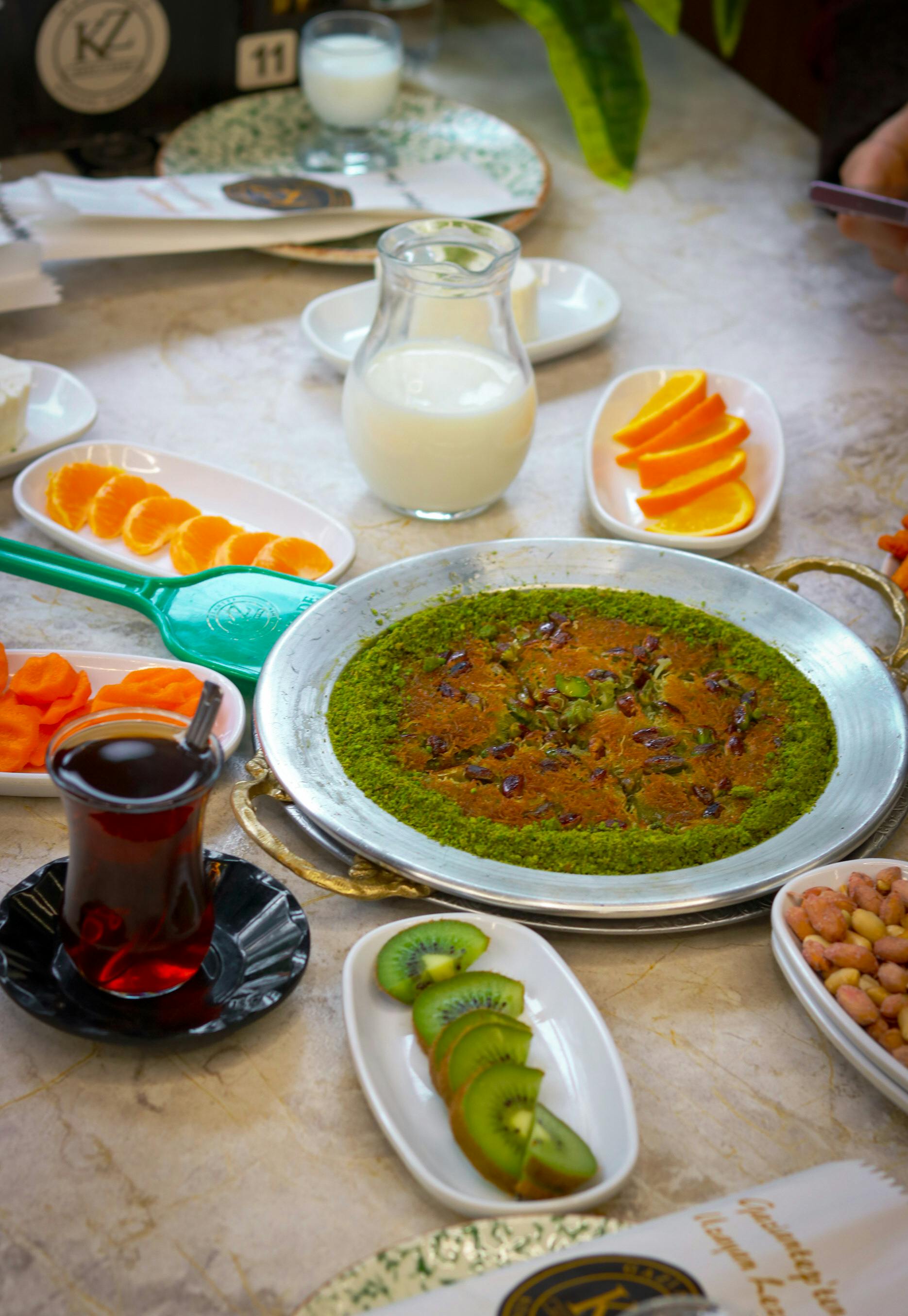 Traditional Turkish breakfast spread featuring Kunefe, tea, and fresh fruits.