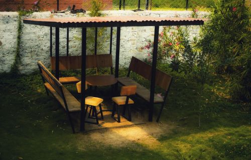 Free Inviting outdoor seating area featuring wooden benches and a table under a shaded canopy. Stock Photo
