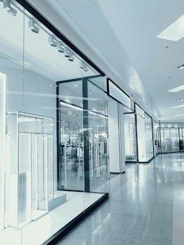 购物中心的走廊明亮而空旷，玻璃展示墙映出倒影