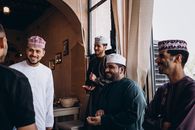 A group of men in traditional Omani clothing chatting indoors in Nizwa, Oman.