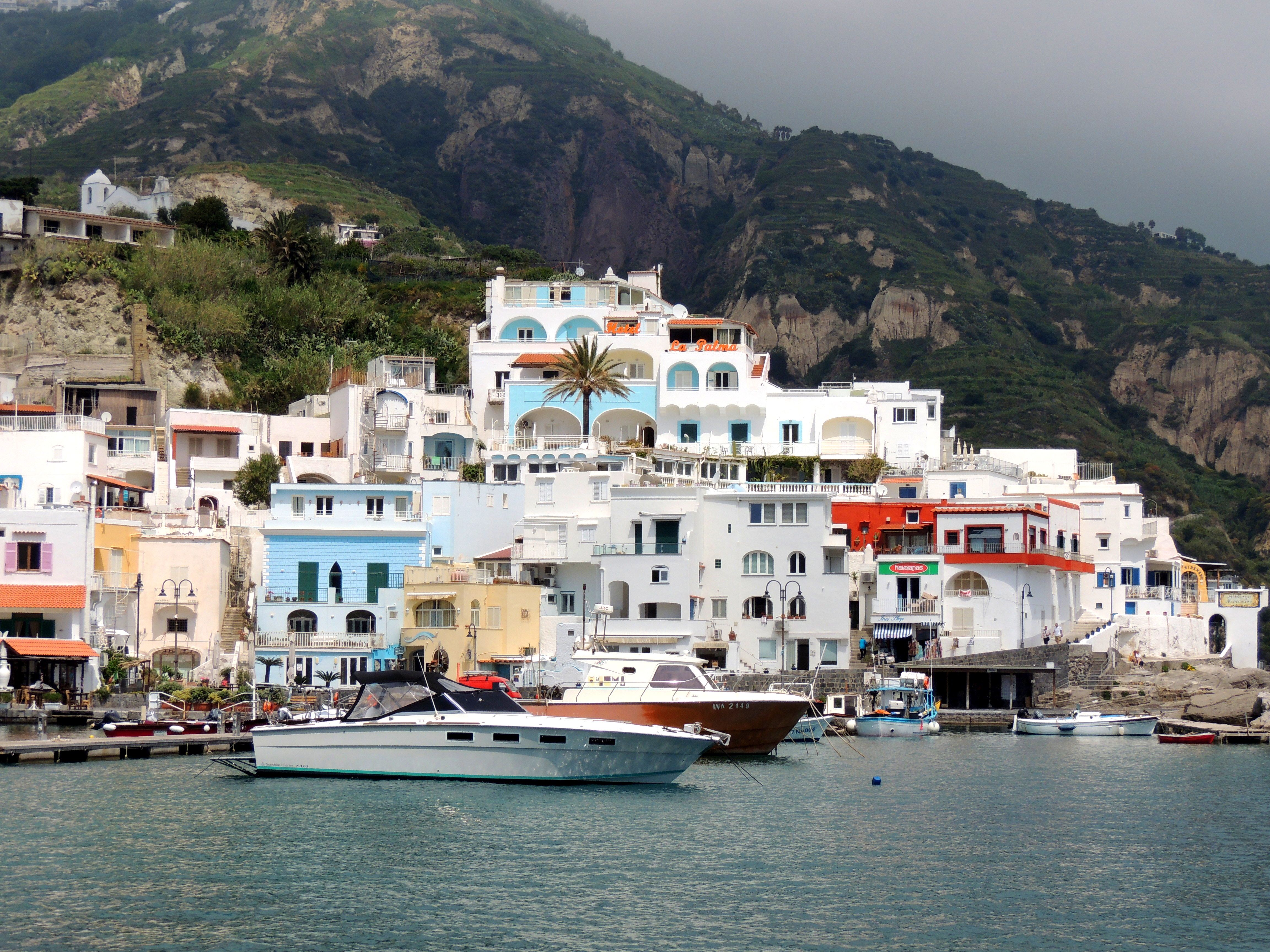 Picturesque view of Sant'Angelo's vibrant buildings and boats along the coast of Ischia, Italy.