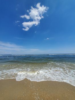 A picturesque beach scene featuring clear skies, gentle waves, and sand. Ideal for summer themes.